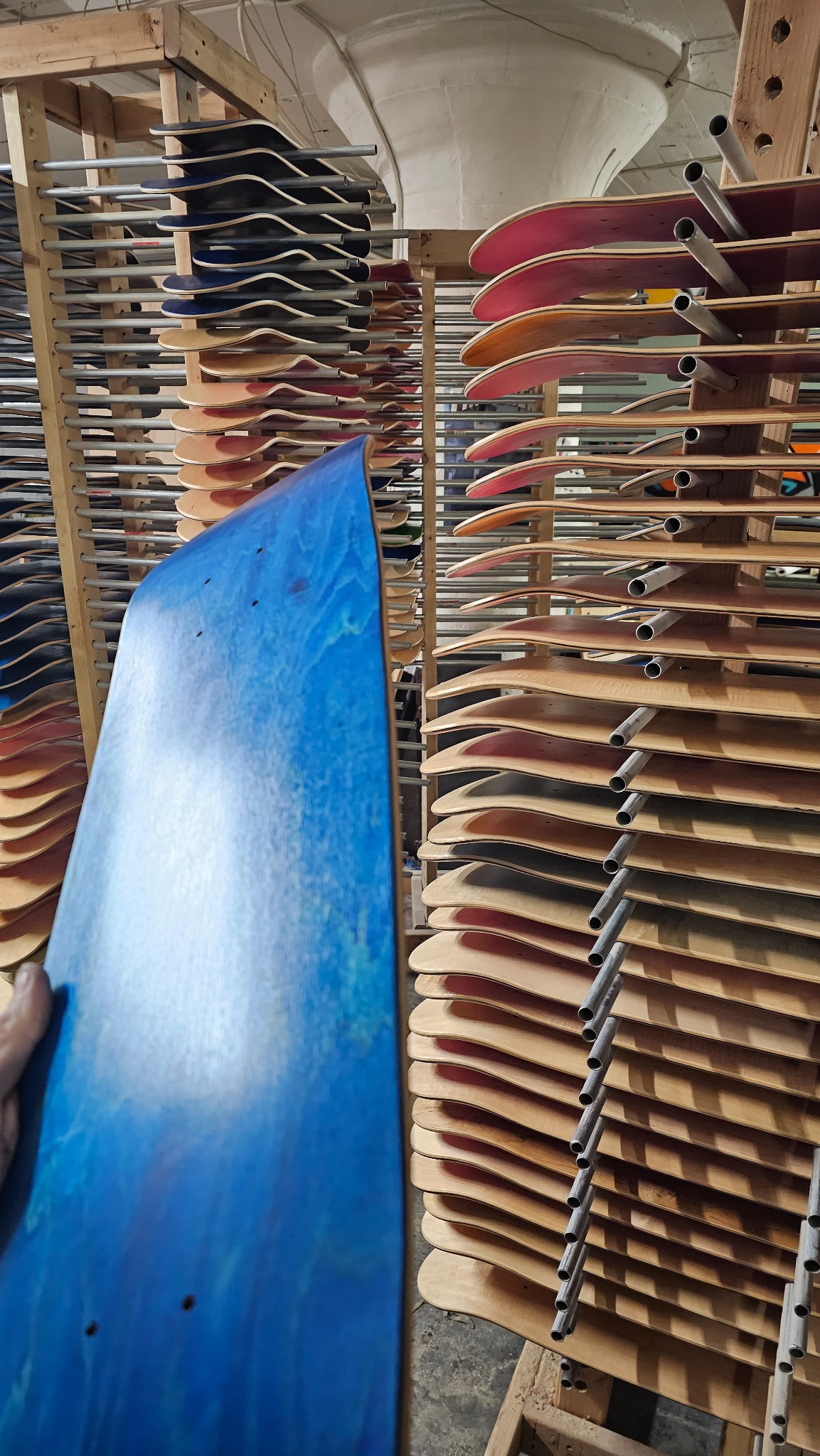 Blue skateboard deck among shop drying racks